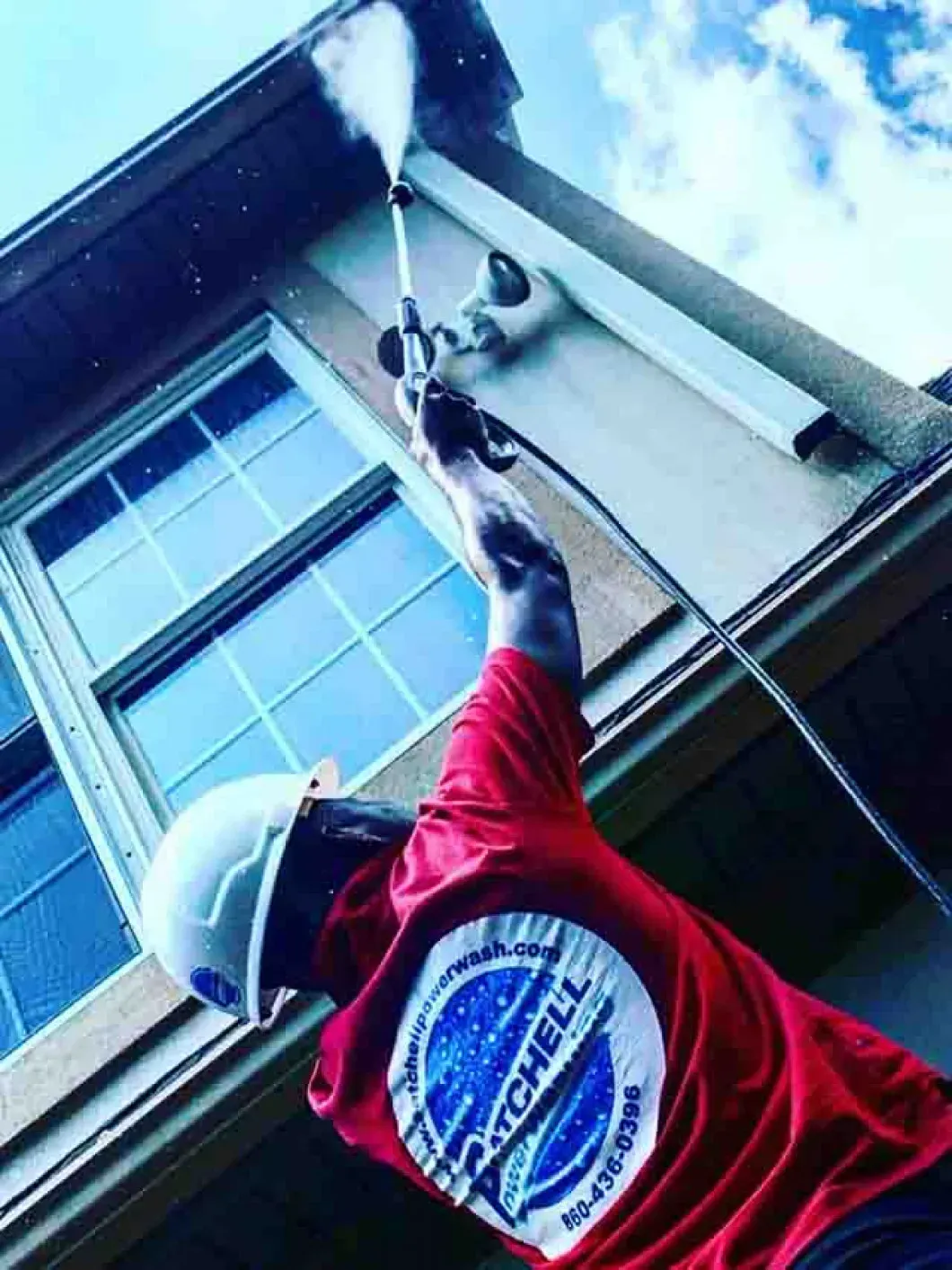 A man is cleaning the side of a building with a high pressure washer.