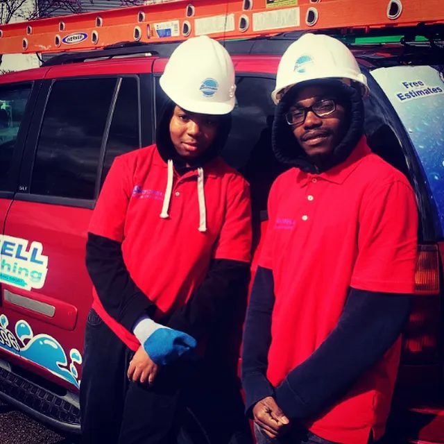 Two men wearing hard hats are standing in front of a vehicle that says ell lighting
