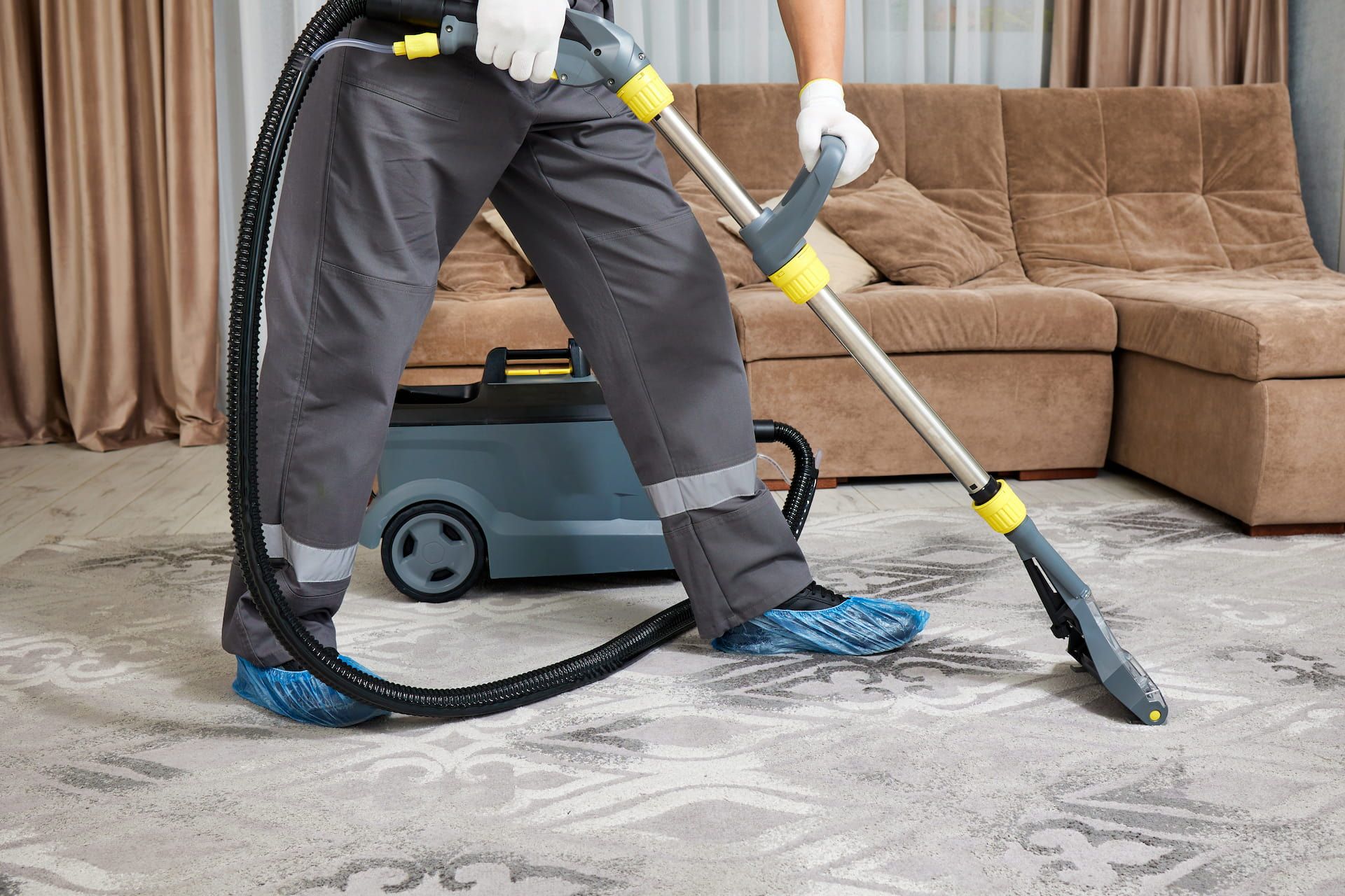 Person cleaning a patterned carpet with an industrial cleaner in a living room.