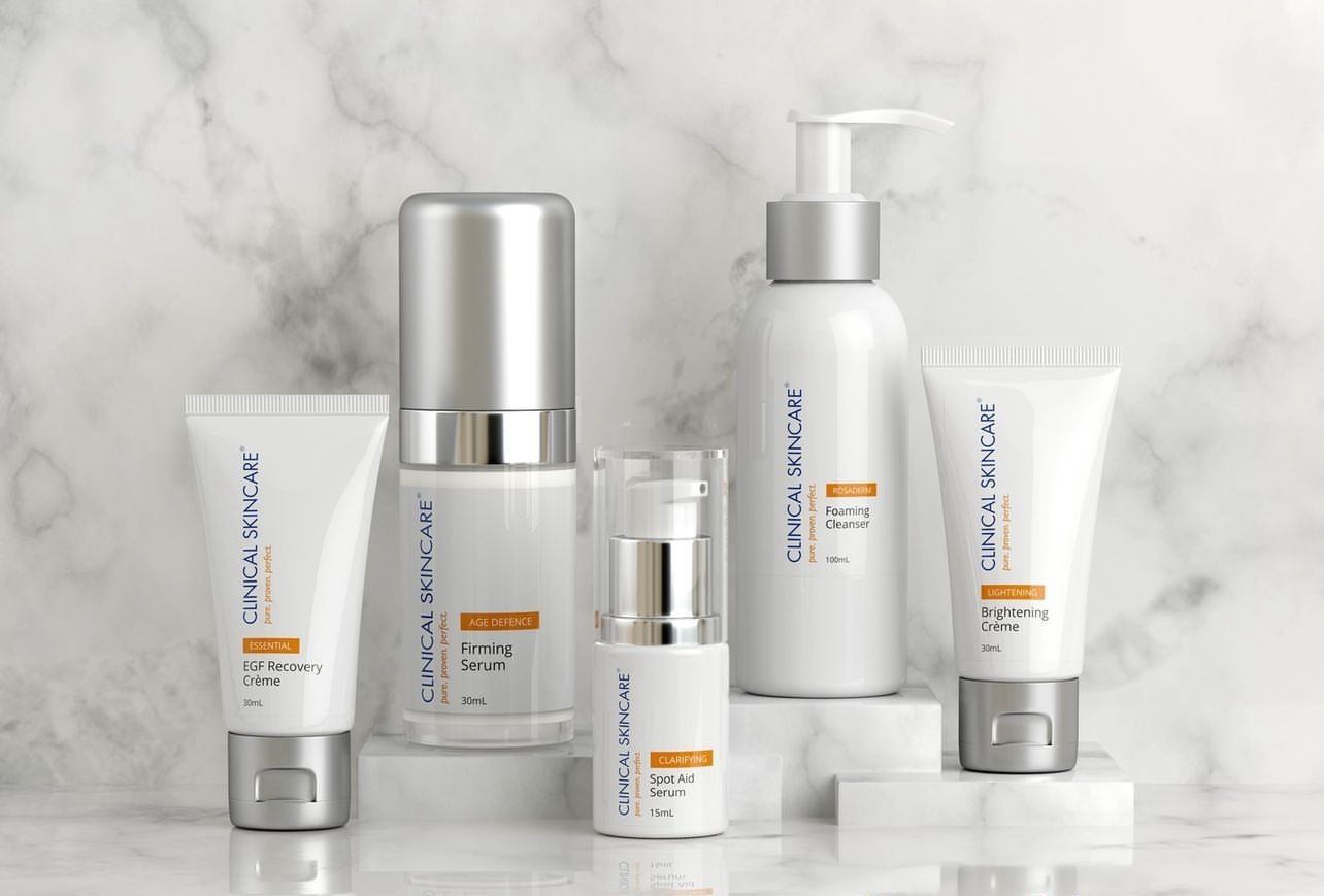 White skincare bottles and tubes arranged on a marble surface against a light gray background
