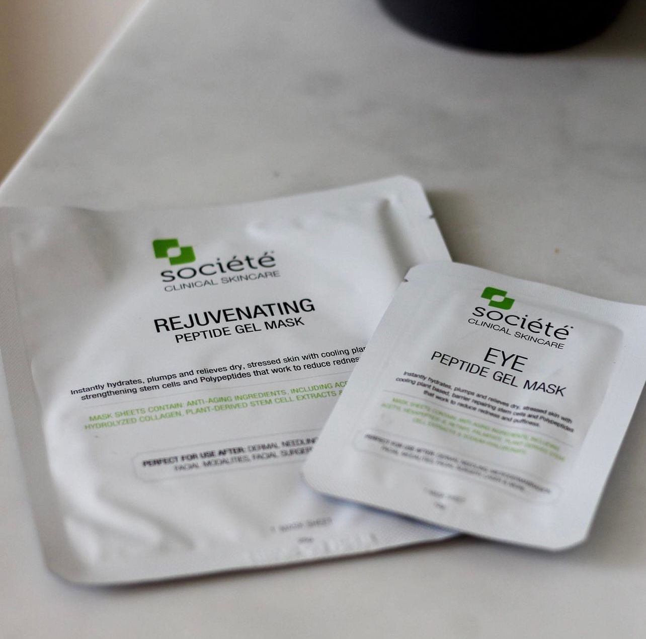Two white skincare sachets on a light surface, one labeled eye repair gel mask and one revitalizing hyaluronic gel mask