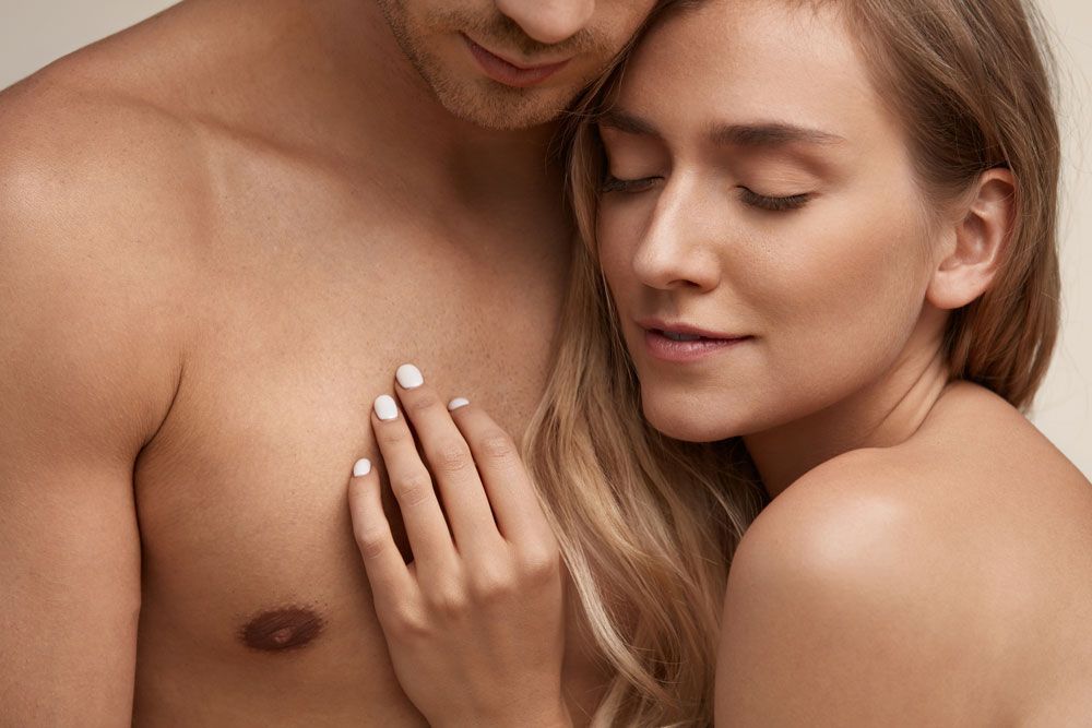 Couple embracing closely, woman resting her hand on the man’s chest with eyes closed