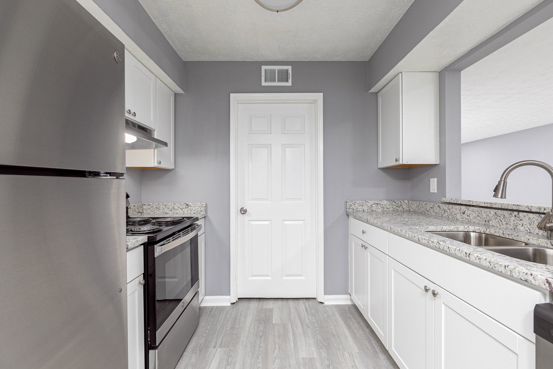 Apartments For Rent In Riverdale, GA - Briar Hill 563 - Kitchen With Granite Countertops, White Cabinets, Vinyl Plank Flooring, Pantry, And Kitchen Bar.