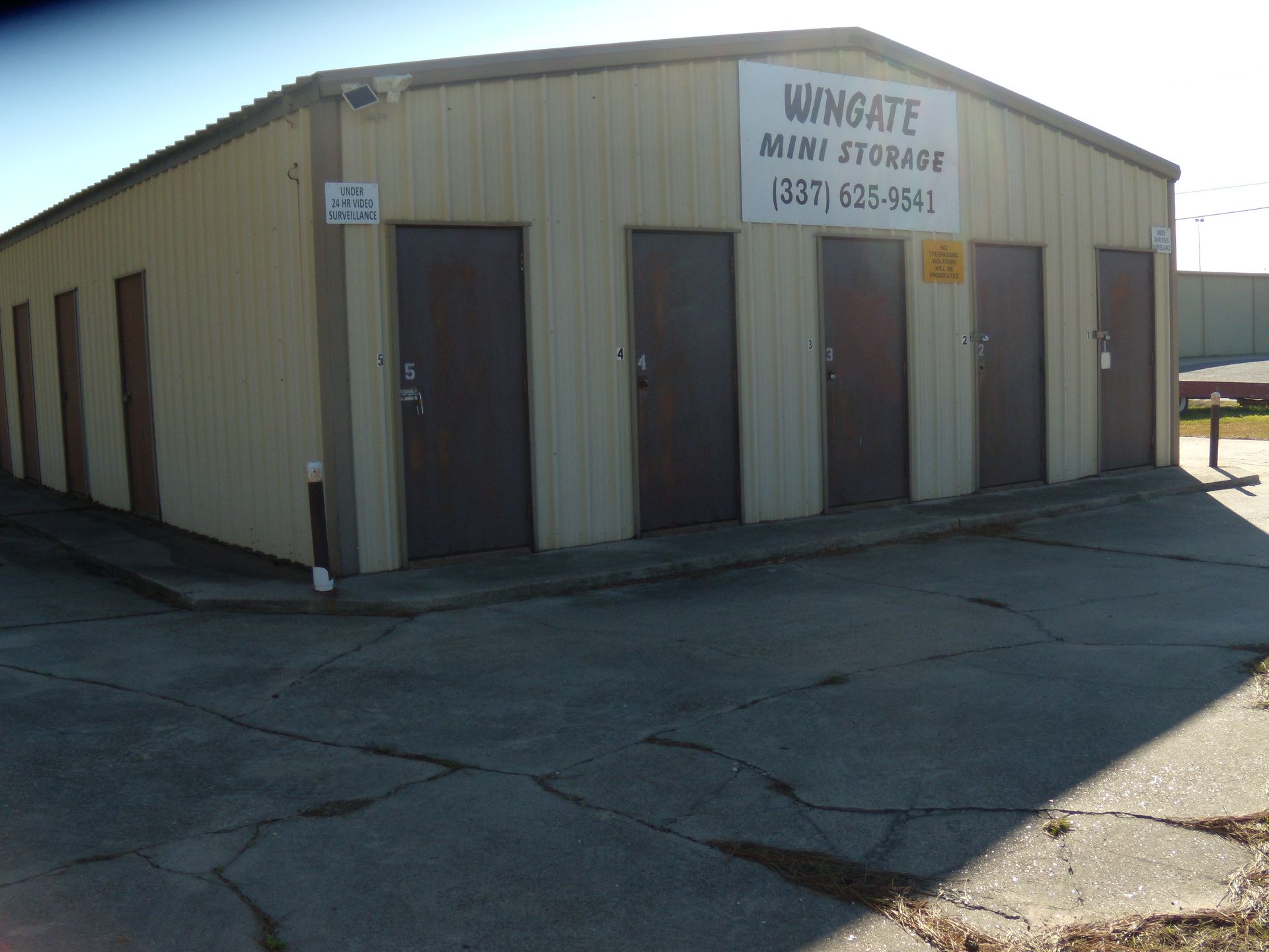 Small beige industrial building with dark doors and a Wingate sign on the front