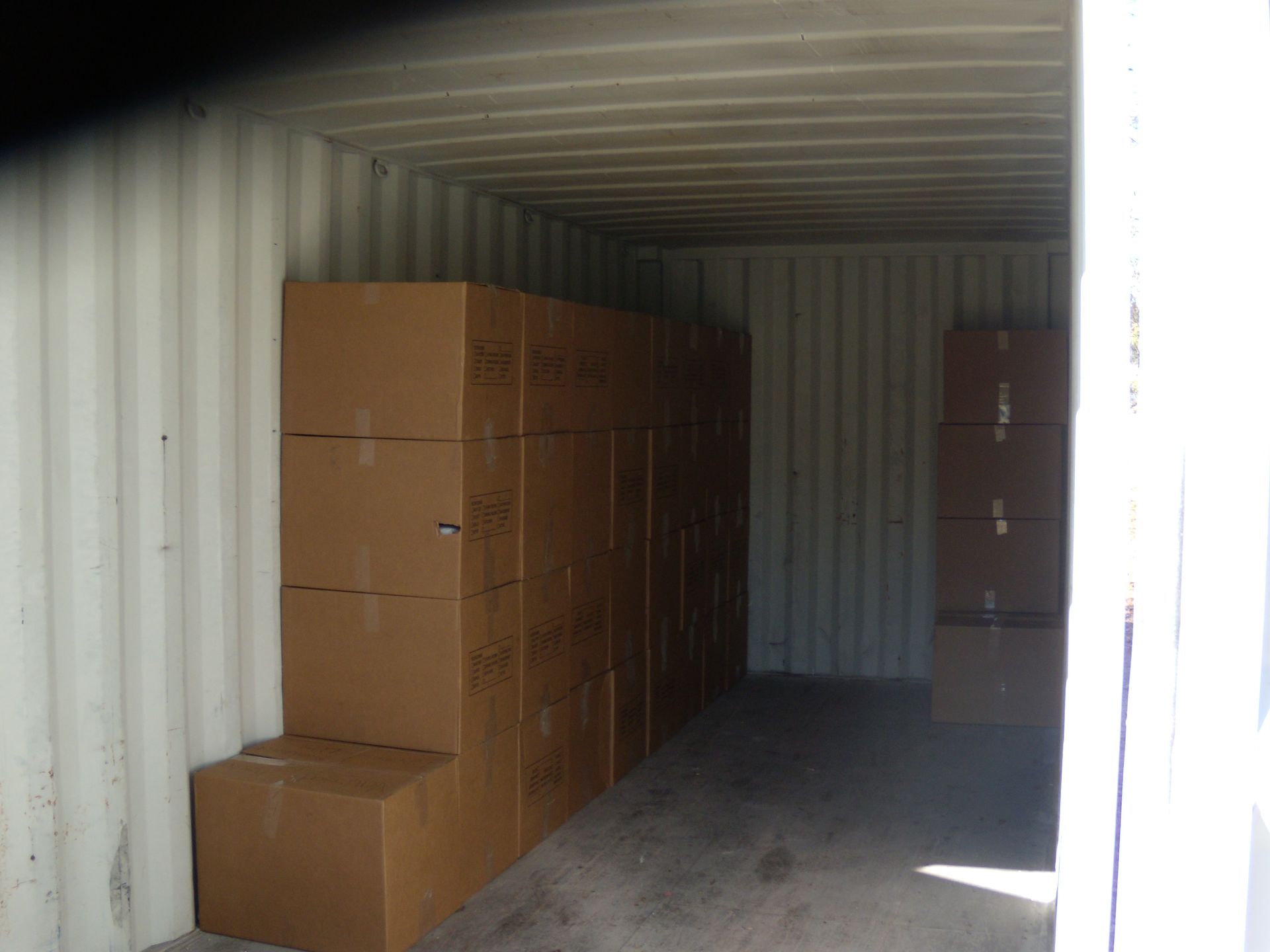 Open shipping container with stacked cardboard boxes inside