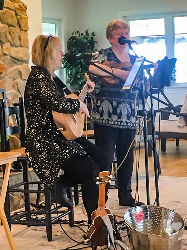 a woman playing a guitar and another woman singing into microphones