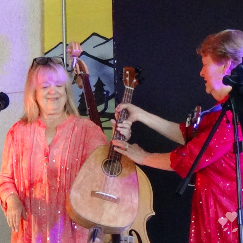 a woman in a red dress is holding a ukulele