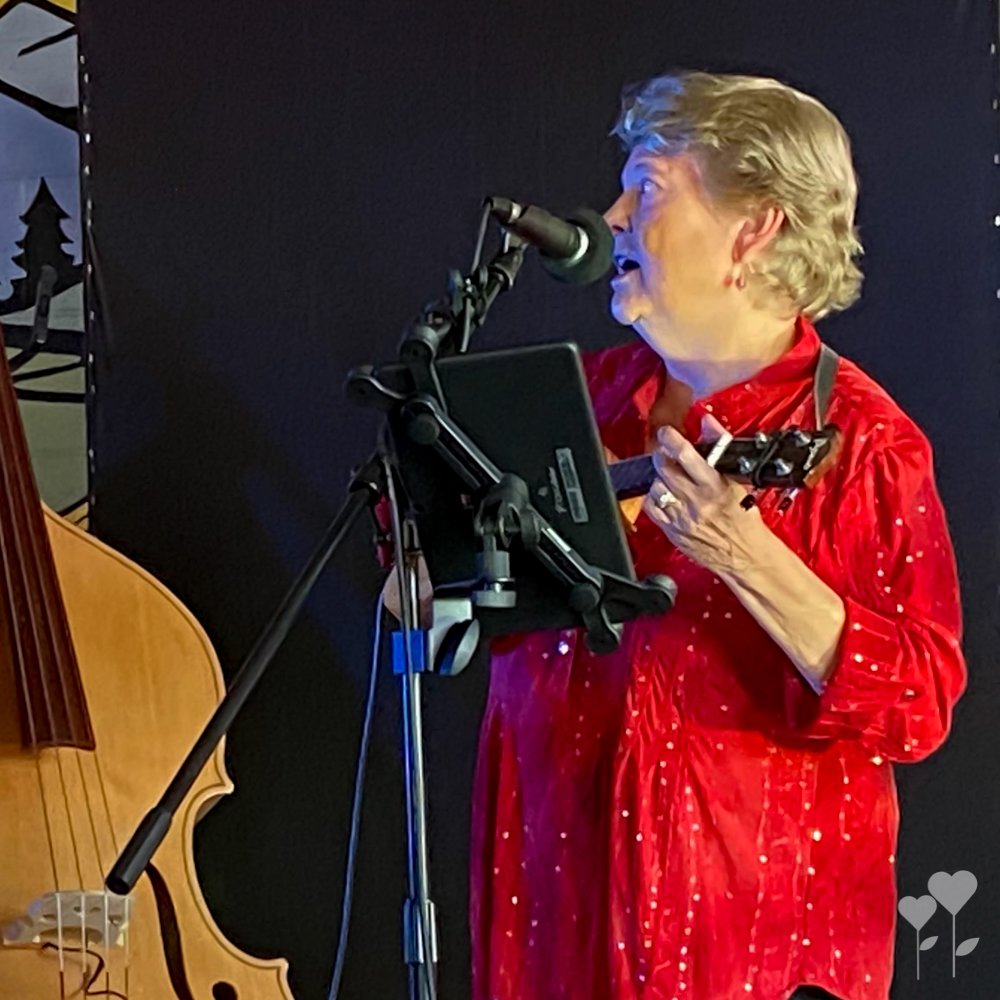 a woman in a red shirt is singing into a microphone