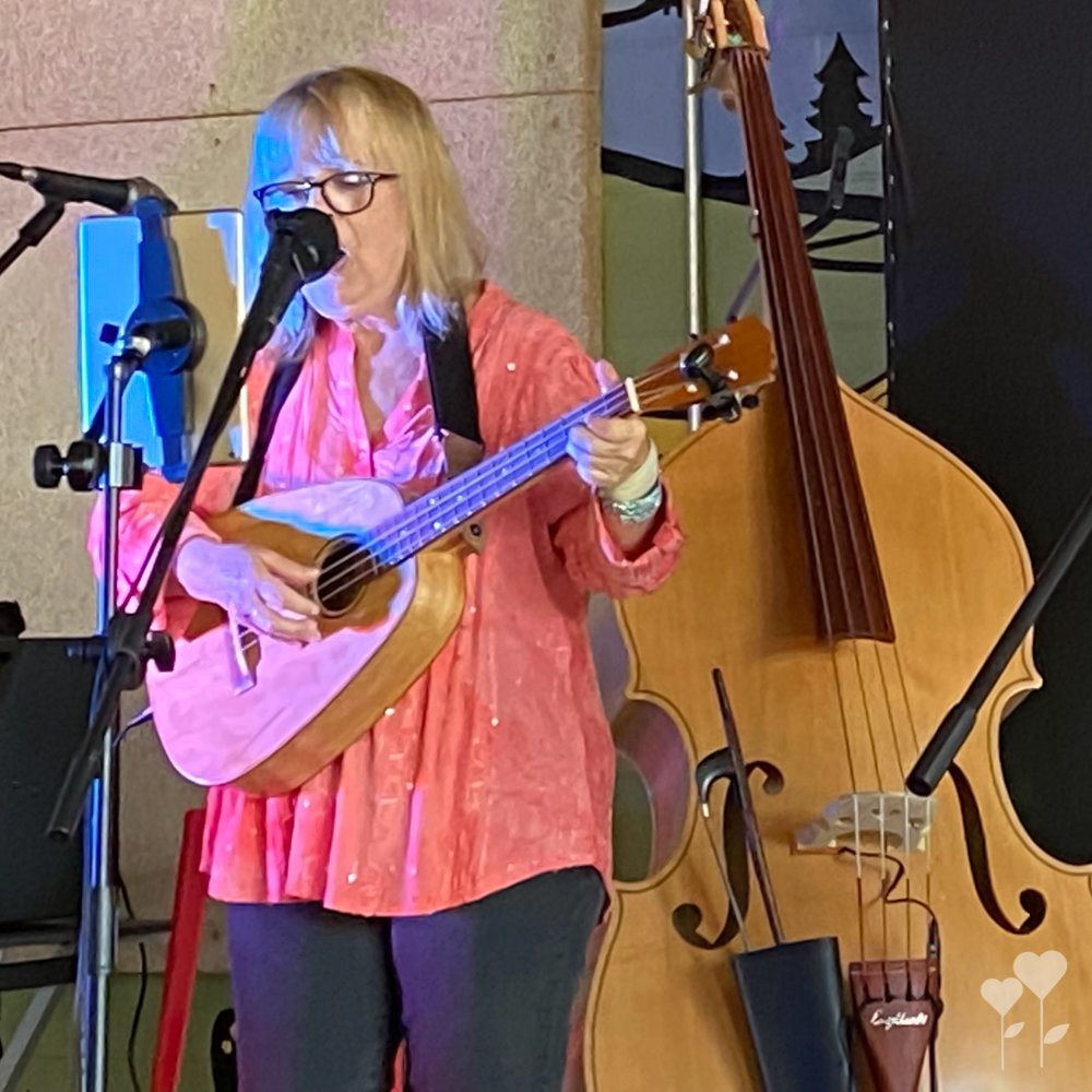 a woman singing into a microphone while playing a ukulele