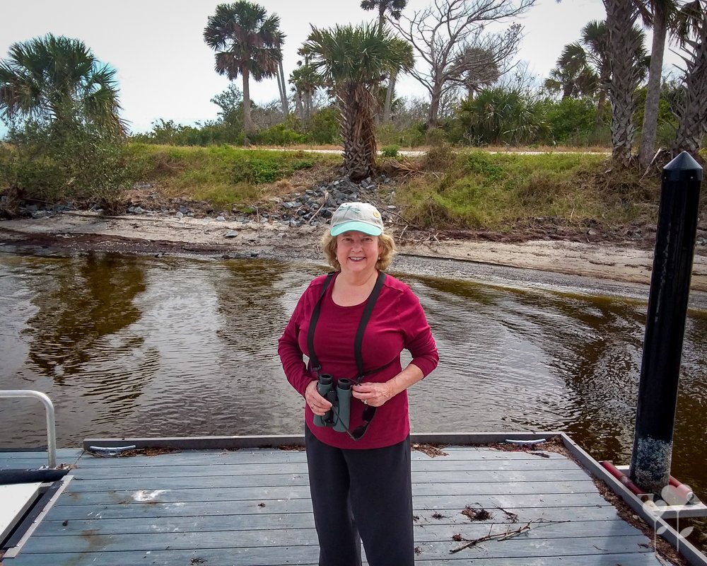a woman standing on a dock holding binoculars
