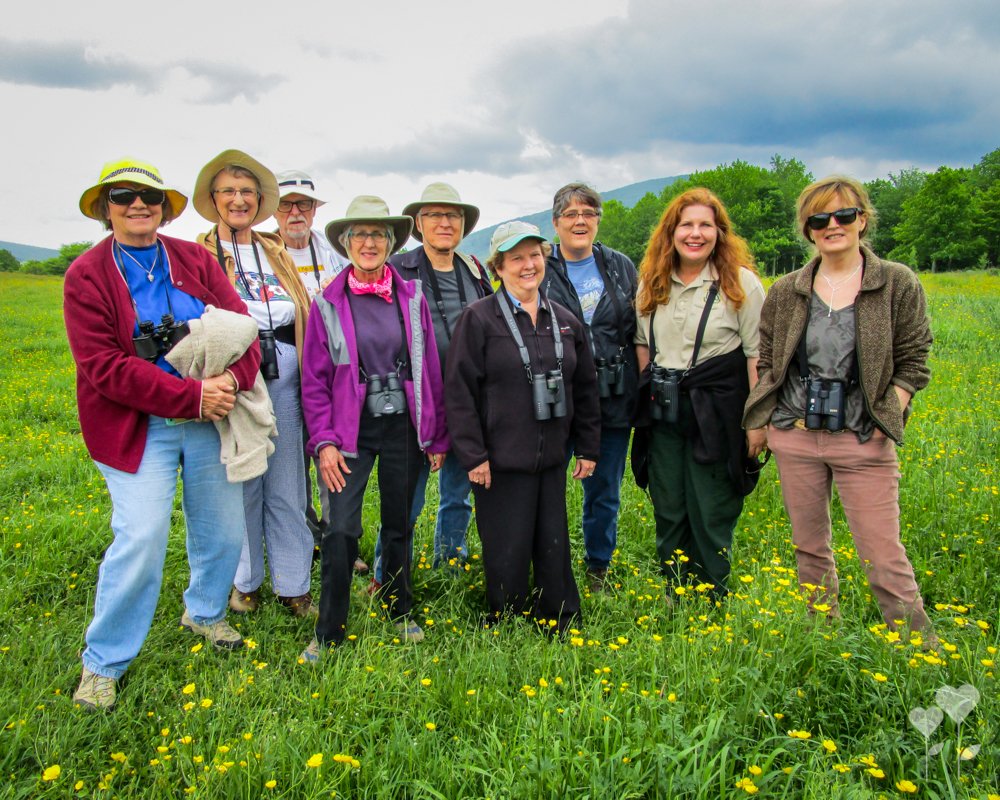 a group of people standing in a field with binoculars around their necks