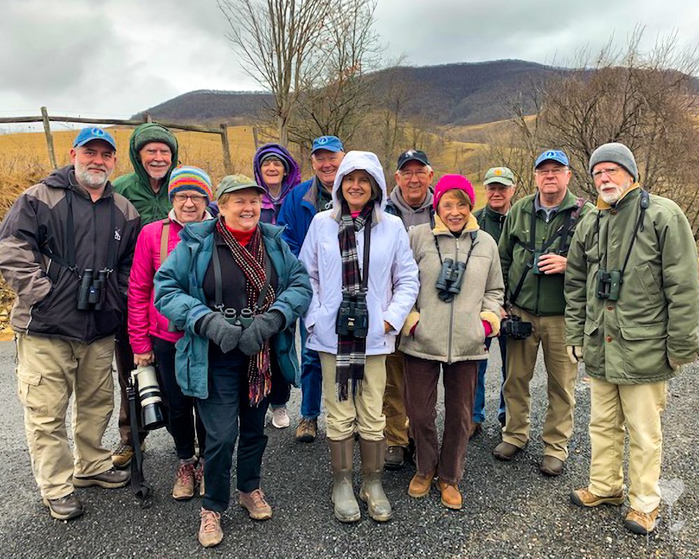 a group of people posing for a picture with one woman wearing a hooded jacket