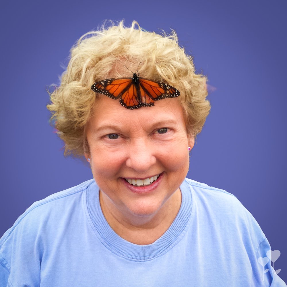 a woman with a butterfly on her head is smiling