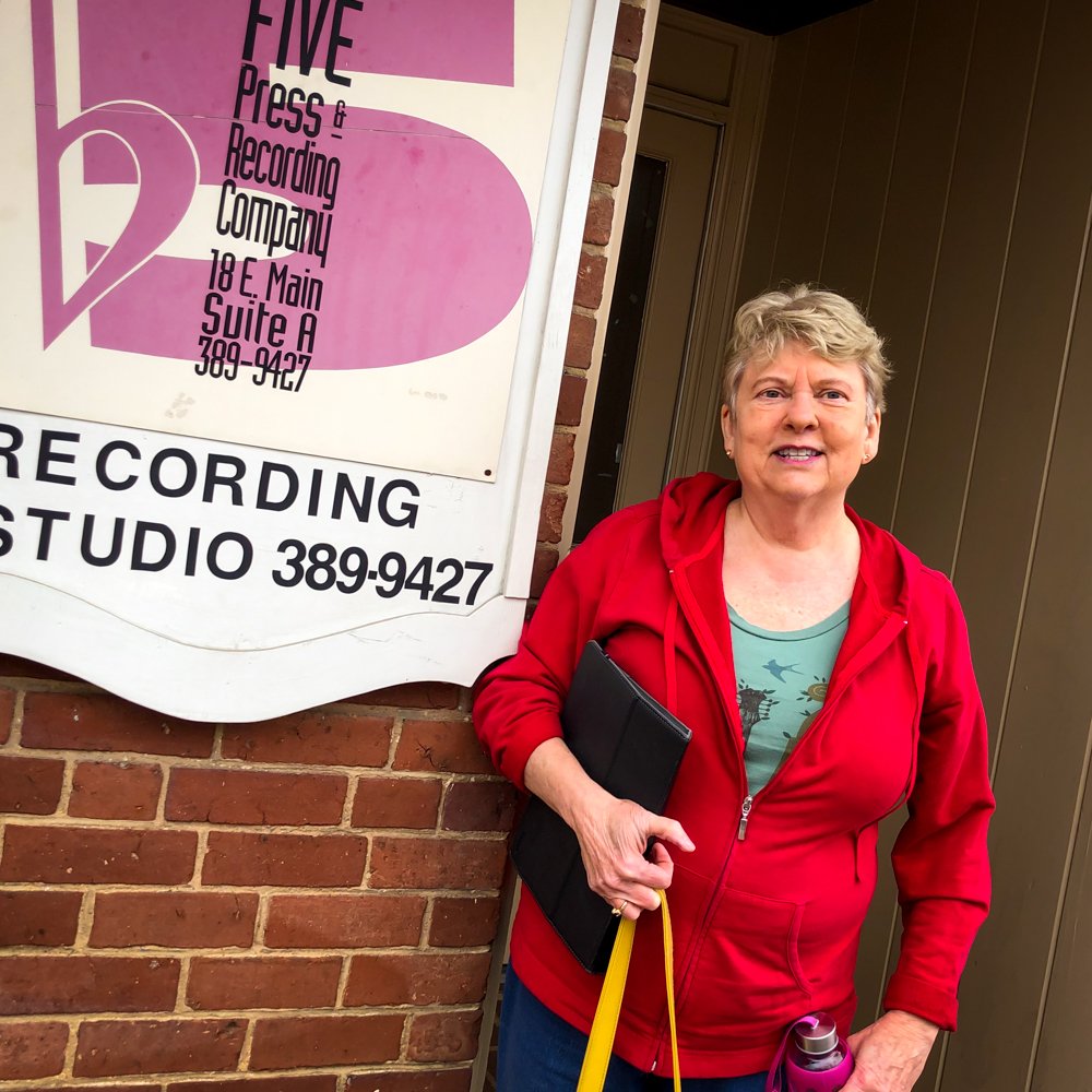 a woman stands in front of a sign for five press & recording company