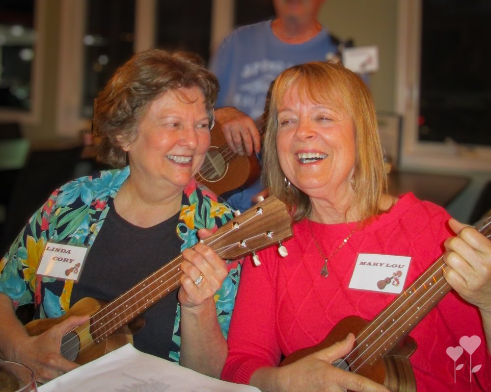 two women are playing ukuleles and one has a name tag that says linda cory