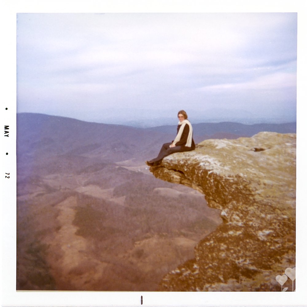 a photo of a woman sitting on a cliff with the date may 1972