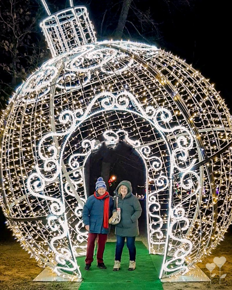 two people standing in front of a large christmas decoration