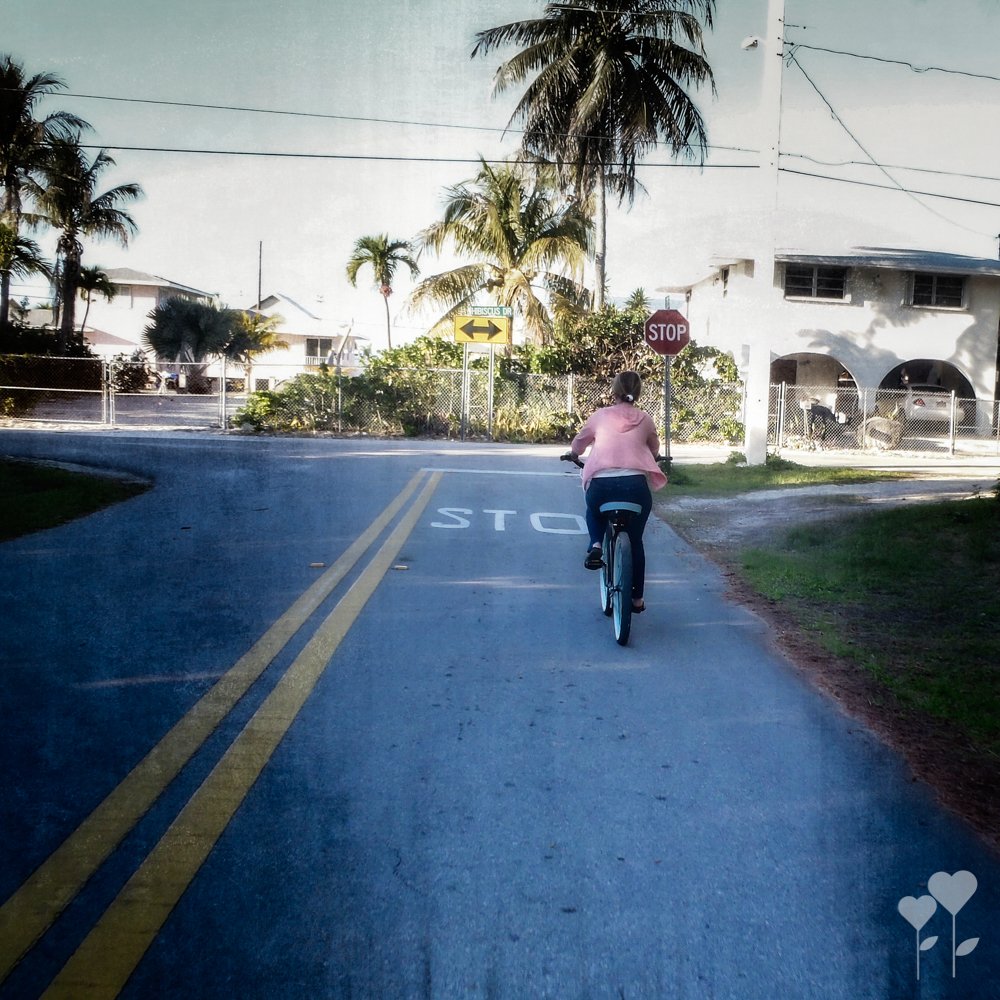 a person riding a bike down a street with a stop sign in the background