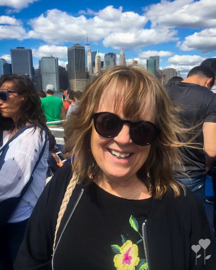 a woman wearing sunglasses stands in front of a city skyline