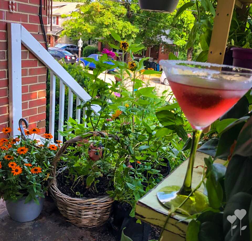 a martini glass on a porch with flowers in the background