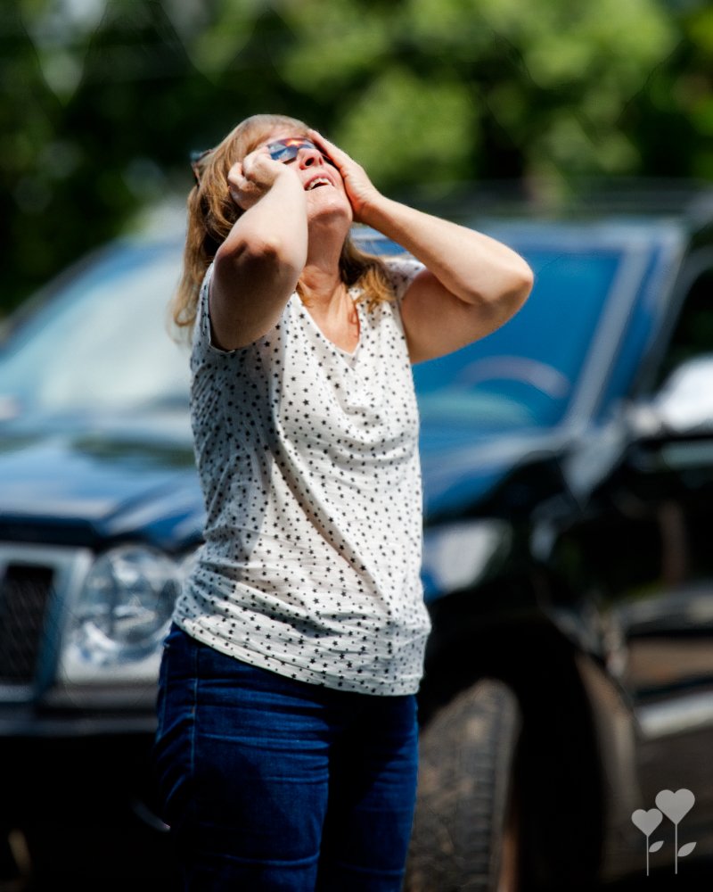 a woman covering her eyes with her hands in front of a car