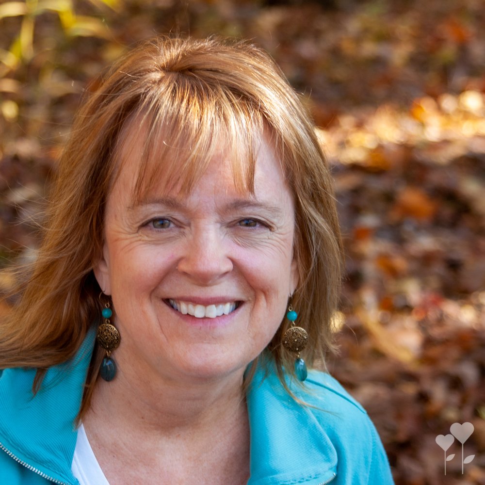 a woman wearing a blue jacket and earrings smiles for the camera