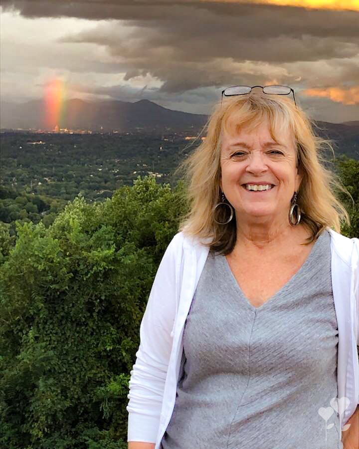 a woman stands in front of a rainbow in the sky