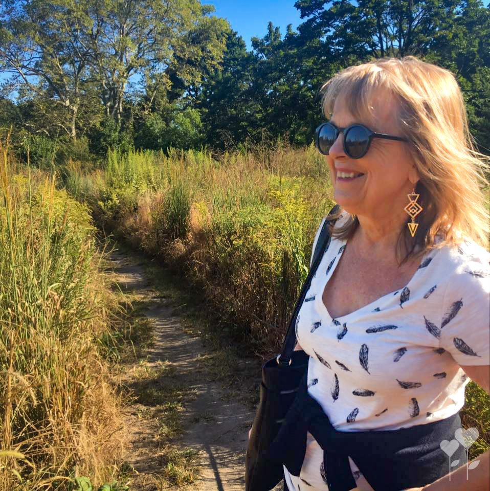 a woman wearing sunglasses is walking down a path