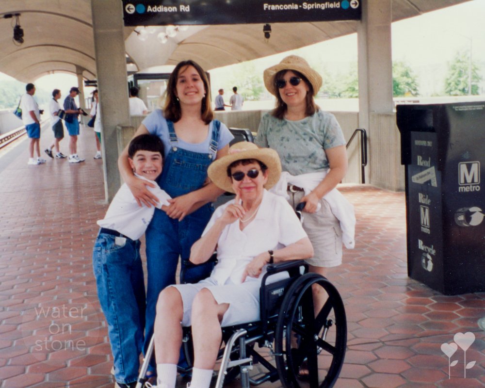 a woman in a wheelchair is surrounded by other people at a metro station