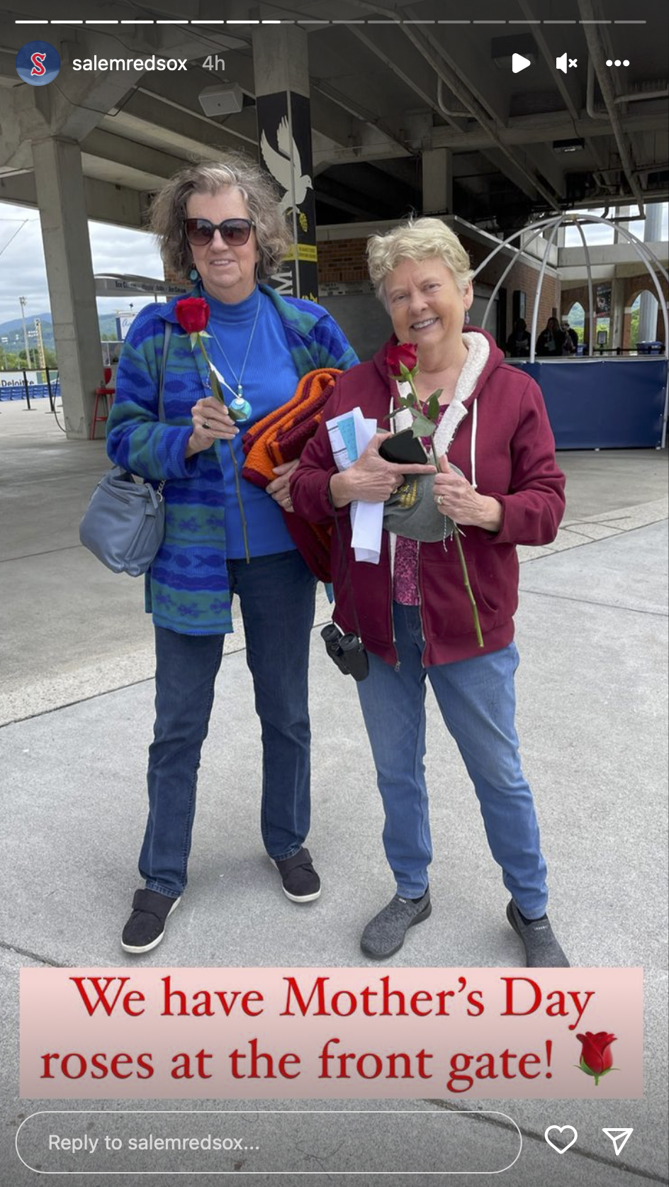 two women holding roses in front of a sign that says we have mother 's day roses at the front gate