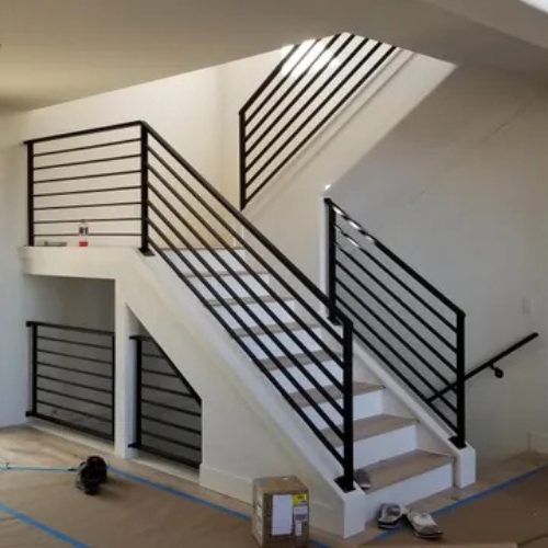Black custom metal horizontal handrails in an interior stair way fabricated and installed by 83MetalCraft, LLC in Bloise idaho