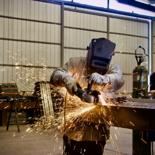 A welder at 83MetalCraft's welding shop in Boise Idaho using a grinder and cutting wheel