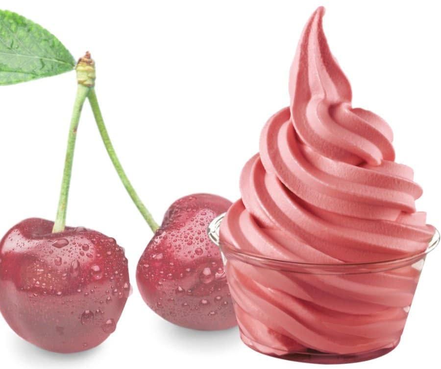 Pink cherries beside a glass of pink soft-serve or frozen dessert
