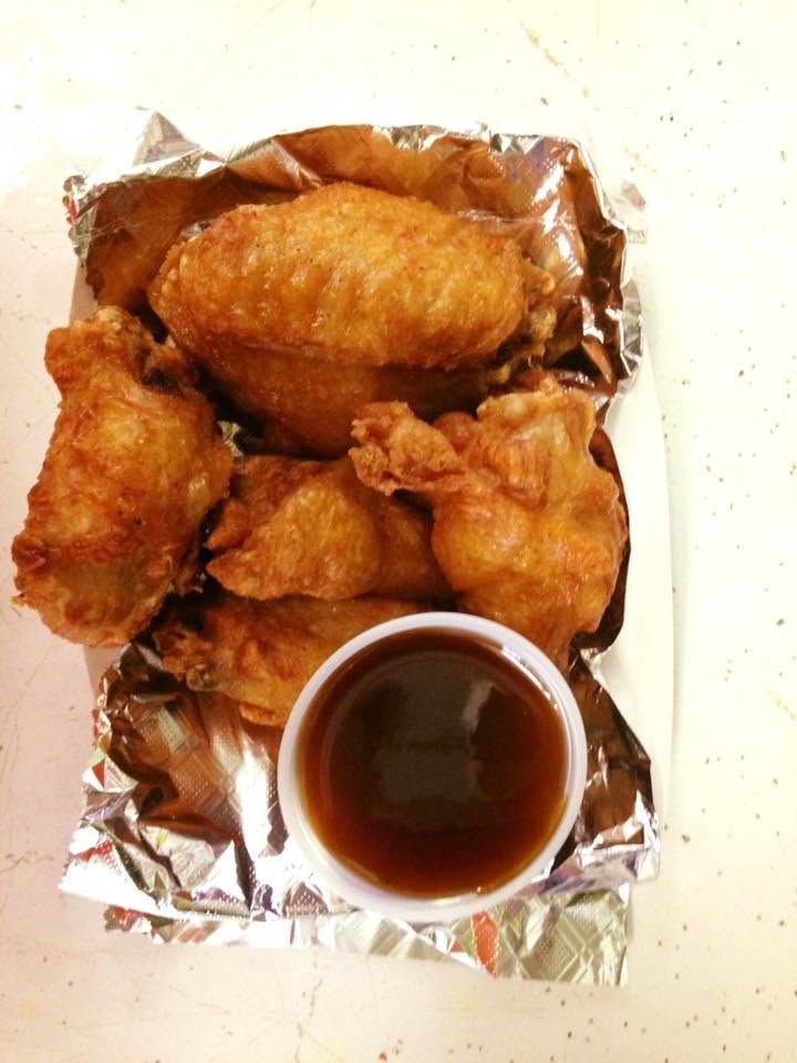 Fried chicken pieces on foil with a cup of dark dipping sauce