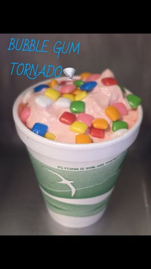 Bubble gum tornado dessert in a green cup topped with colorful candy pieces and pink cream