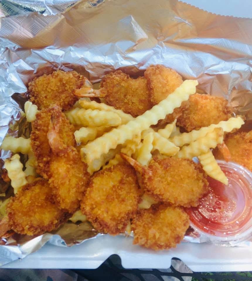 Crinkle fries and breaded chicken nuggets in a tray with dipping sauce on foil wrap