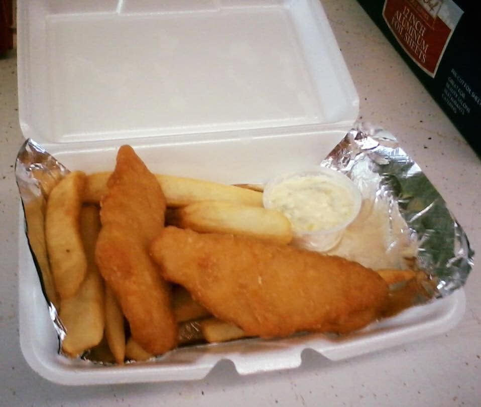 Takeout box with fried fish fillets, fries, and a cup of tartar sauce