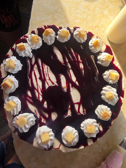 Chocolate cake with white whipped cream dollops and dark berry drizzle on a table