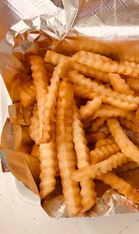 Open bag of crinkle-cut French fries on a white surface