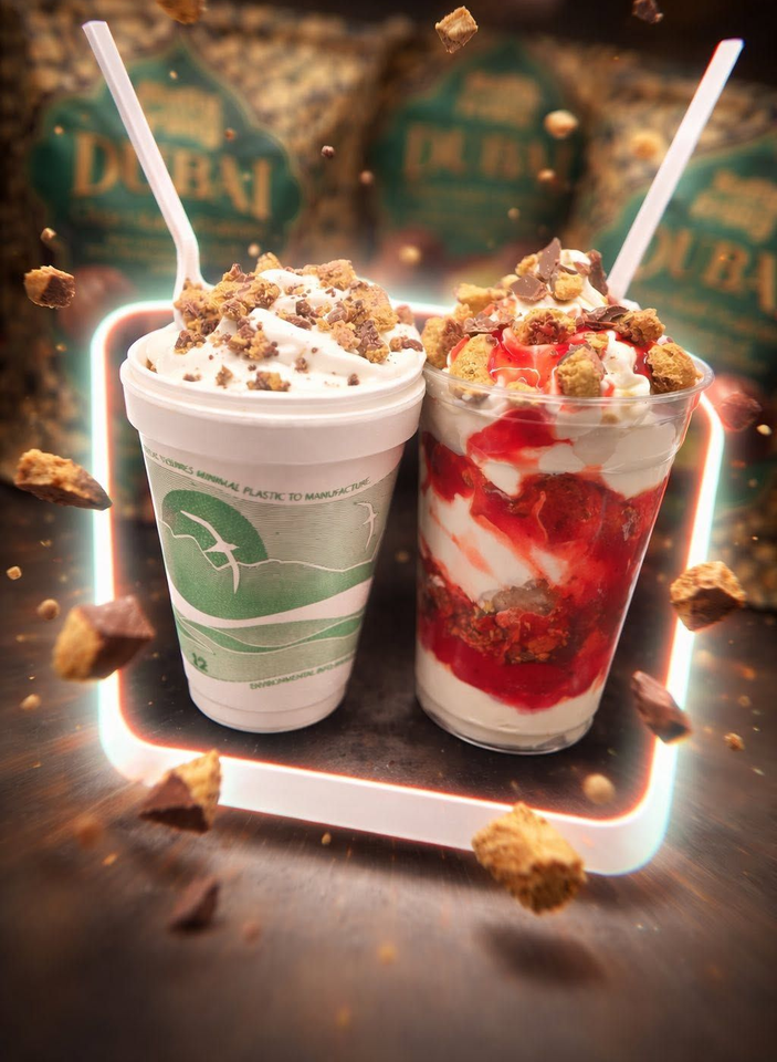 Two dessert drinks with whipped cream and toppings, one green and one red, on a dark festive background