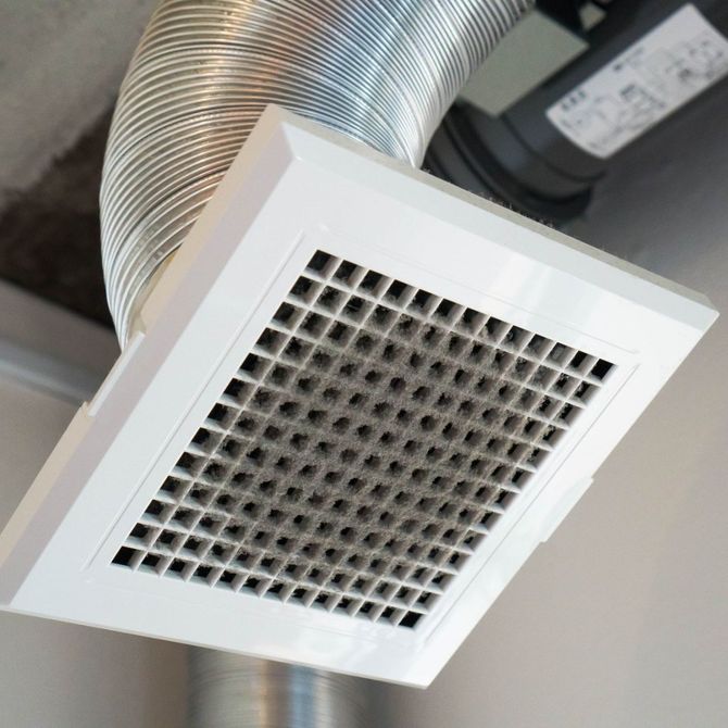 A close up of an air vent with a hose attached to it