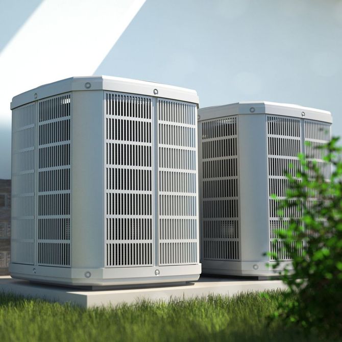 Two air conditioners are sitting next to each other in the grass.
