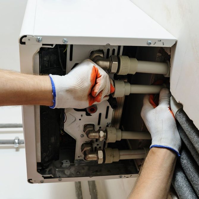A person wearing gloves is working on a boiler