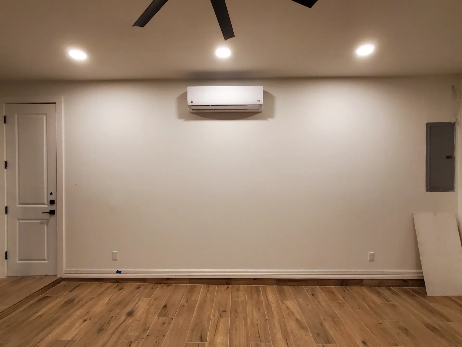 An empty living room with hardwood floors and a ceiling fan.