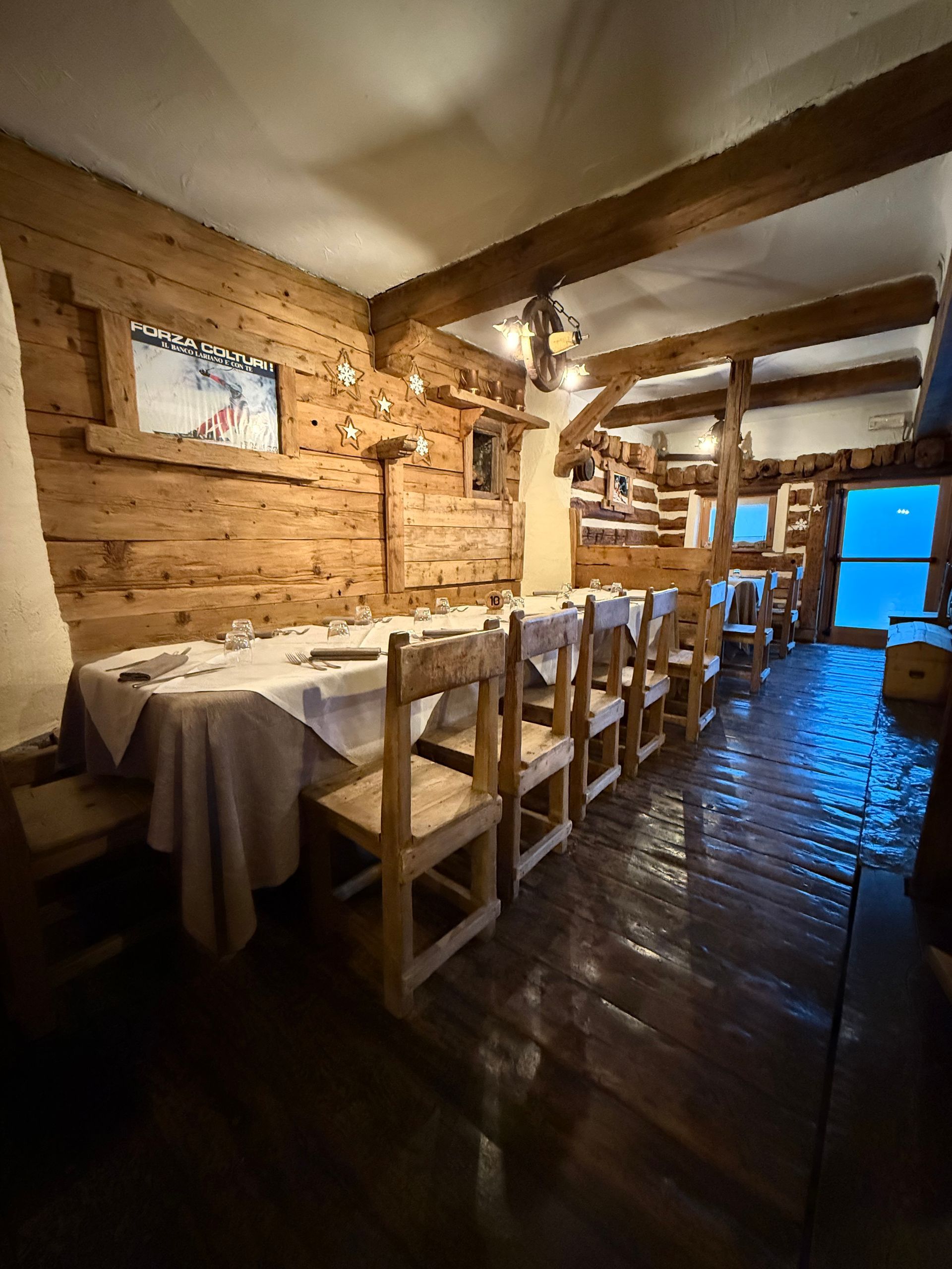 Un ristorante con tavoli e sedie in legno e un muro in pietra