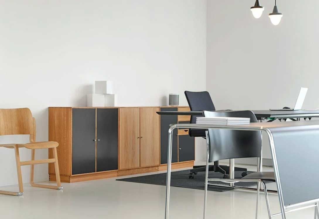 Modern office with wooden cabinets, chairs, and a desk with a laptop and chair in a bright room