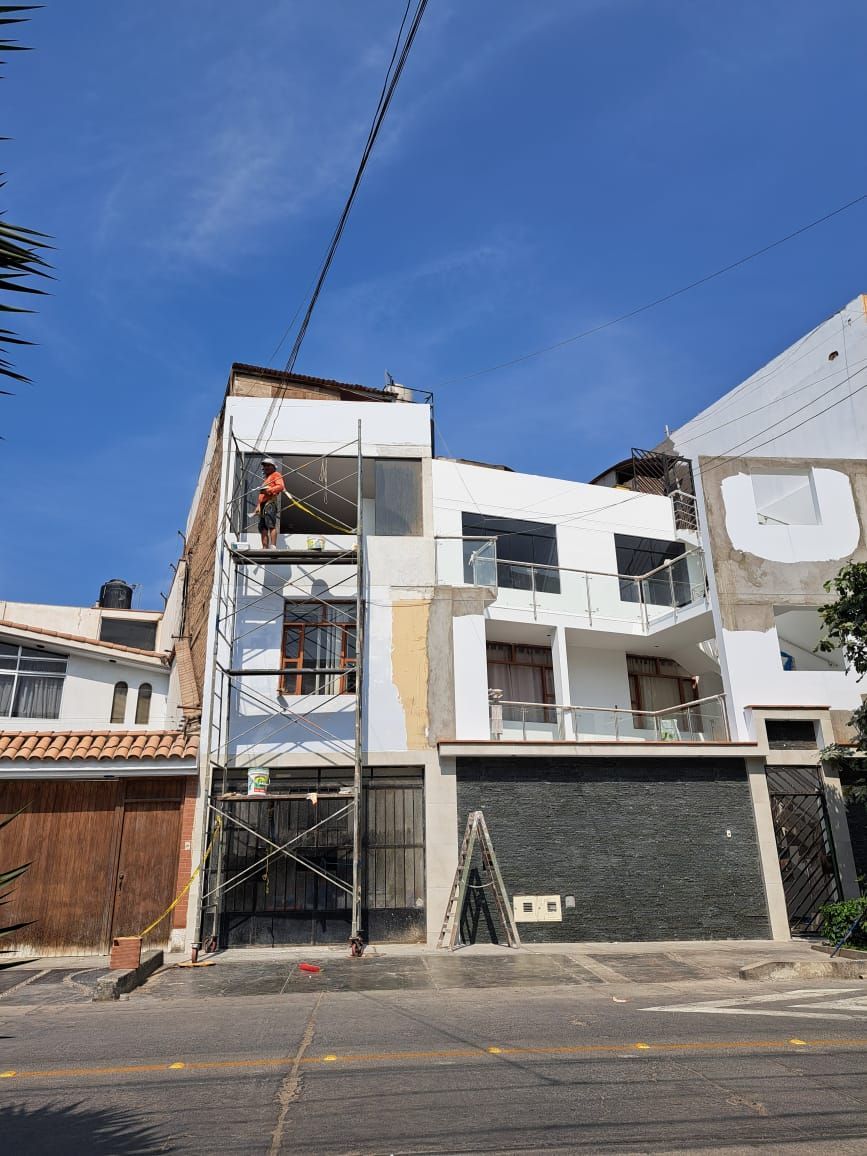 Un grupo de seis personas sostiene papeles, de pie en una habitación luminosa con grandes ventanales.