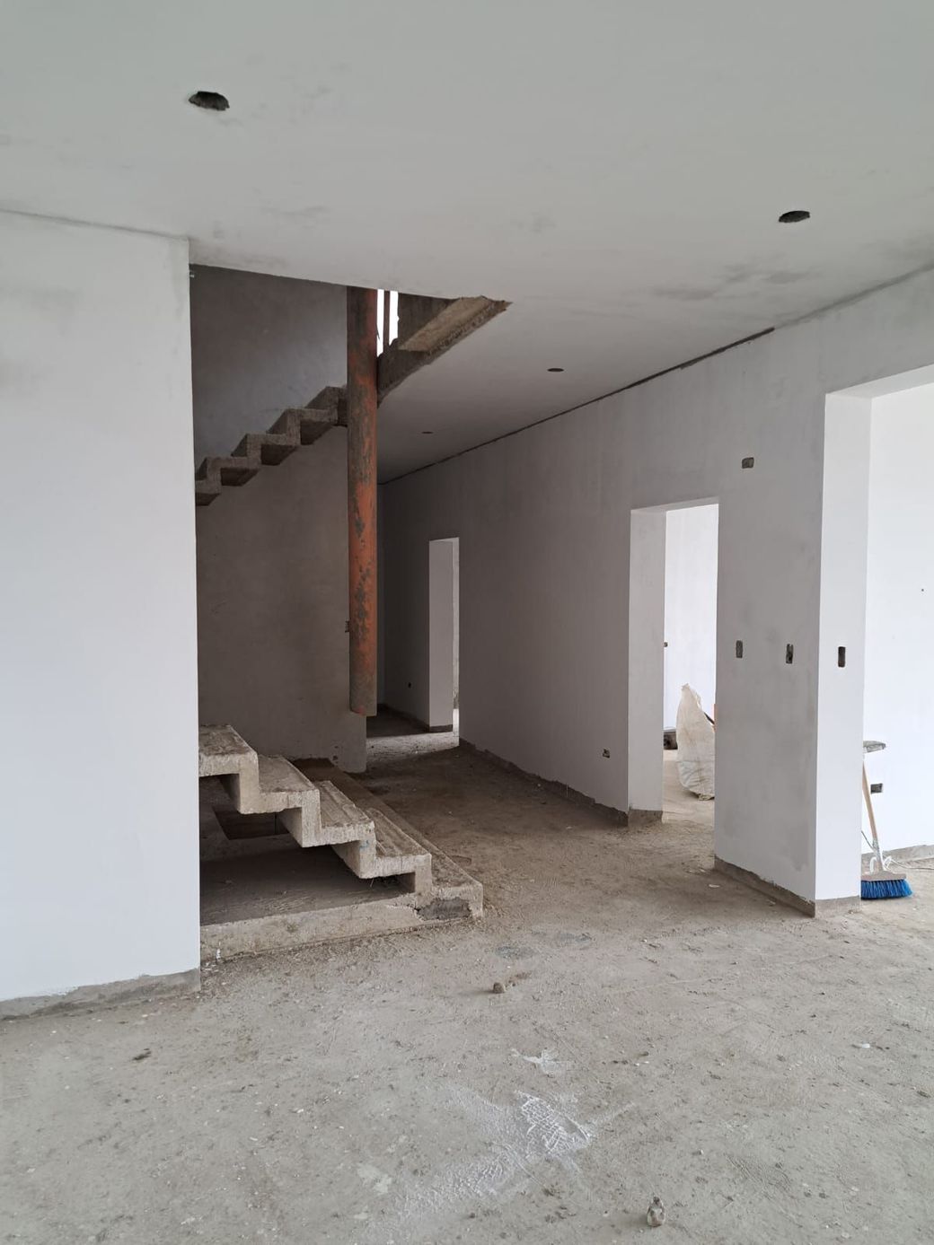 Dos personas pintando una pared de color beige en una sala de estar luminosa con una gran ventana.