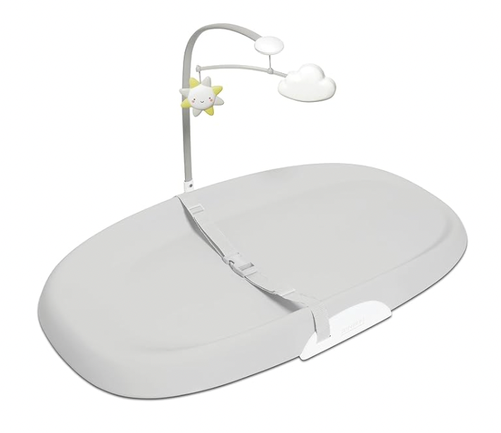 A white baby changing table with a mobile attached to it.