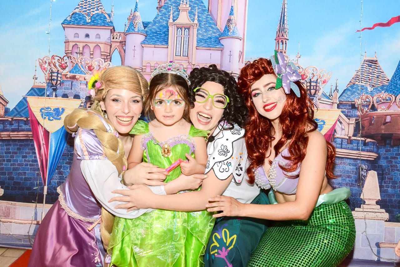 Cuatro personas disfrazadas de personajes de Disney posan juntas frente a un castillo de fondo.
